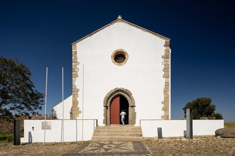 White facade with stone quoins and arched doorway under clear blue sky