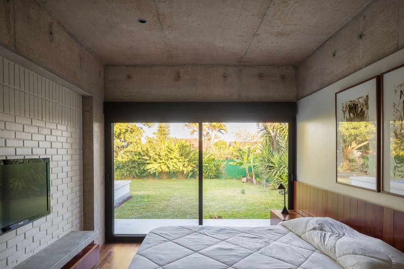 Bedroom with white brick accent wall and sliding glass doors overlooking a backyard lawn at sunset