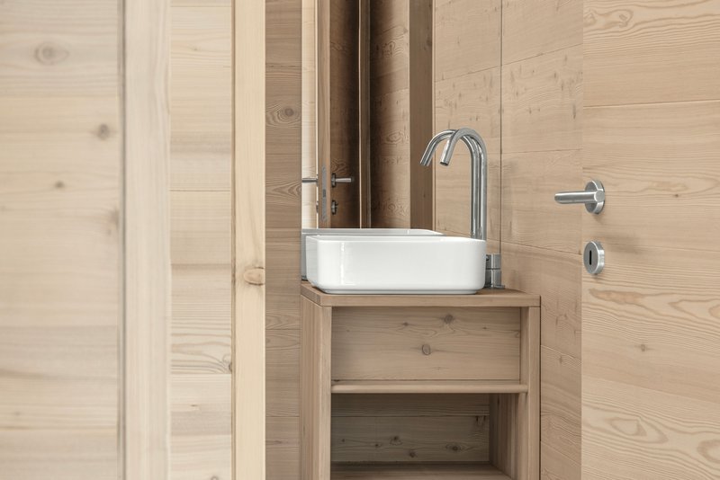 Bathroom vanity with white vessel sink and chrome fixtures against timber plank walls