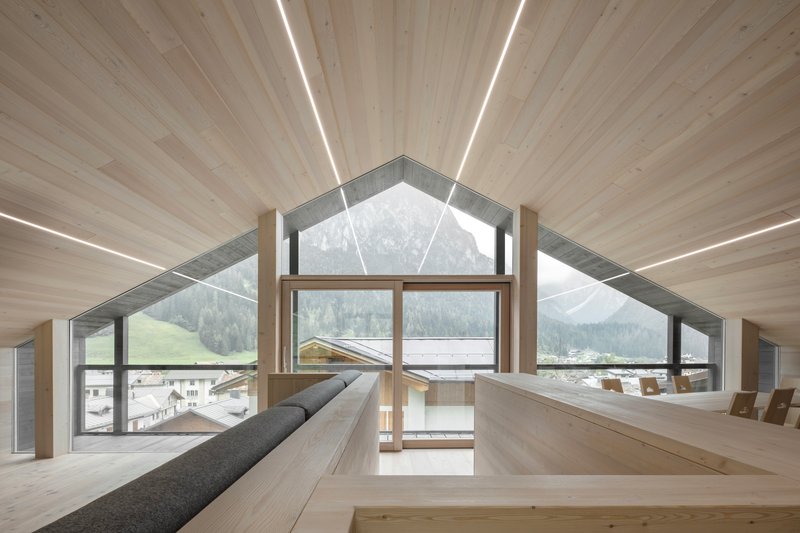 Attic room with gabled window framing mountain view and built-in benches along timber walls