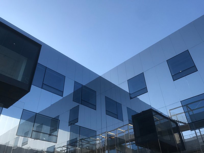 Courtyard view showing white and grey panels with irregularly placed protruding windows at dusk