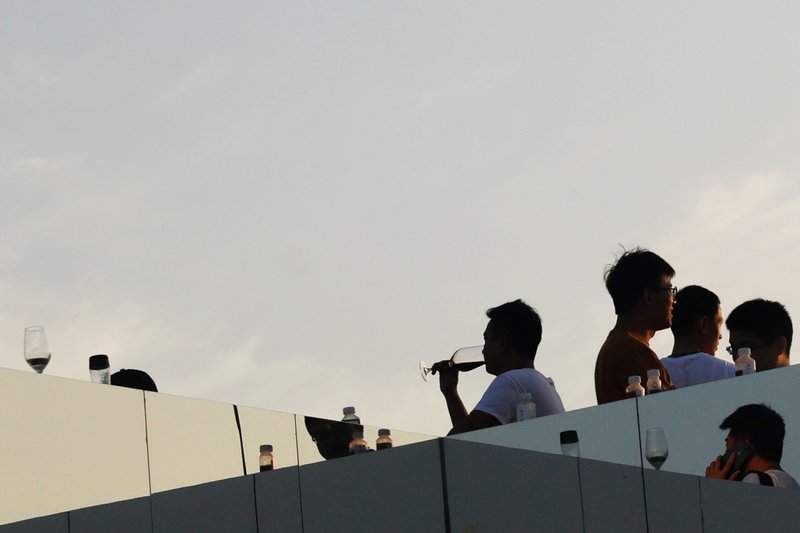 Frosted glass rooftop balustrade with figures silhouetted against the sunset sky