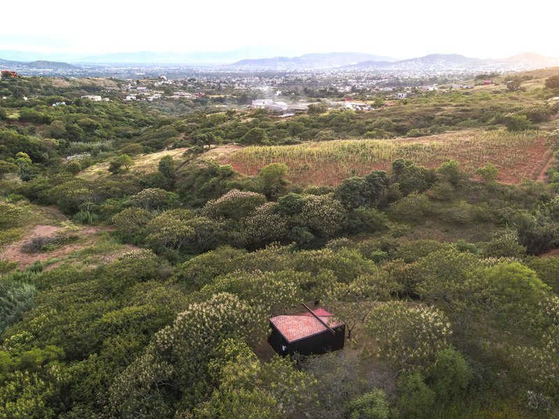 Aerial view of the compact structure with red canopy nestled in dense scrubland vegetation