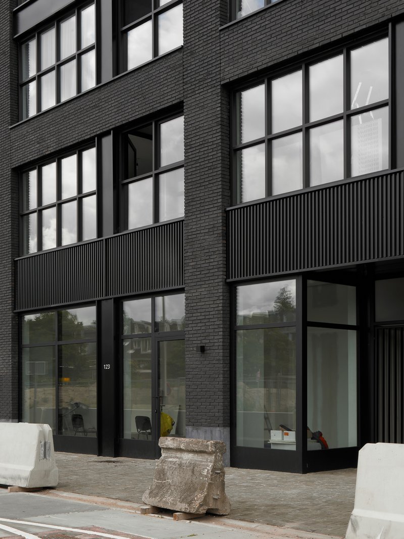 Ground floor entrance with black-framed glazing, fluted metal panels, and dark brick facade