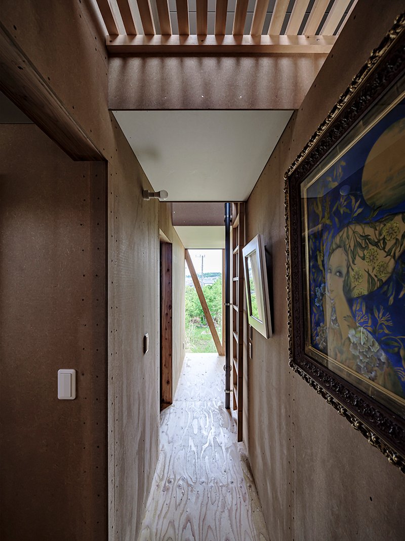 Concrete corridor with exposed ceiling joists and diagonal timber brace visible through open doorway