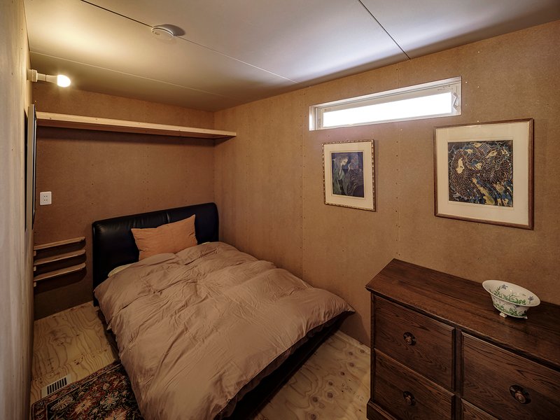 Bedroom with horizontal plywood wall panels and high ribbon window under a white ceiling