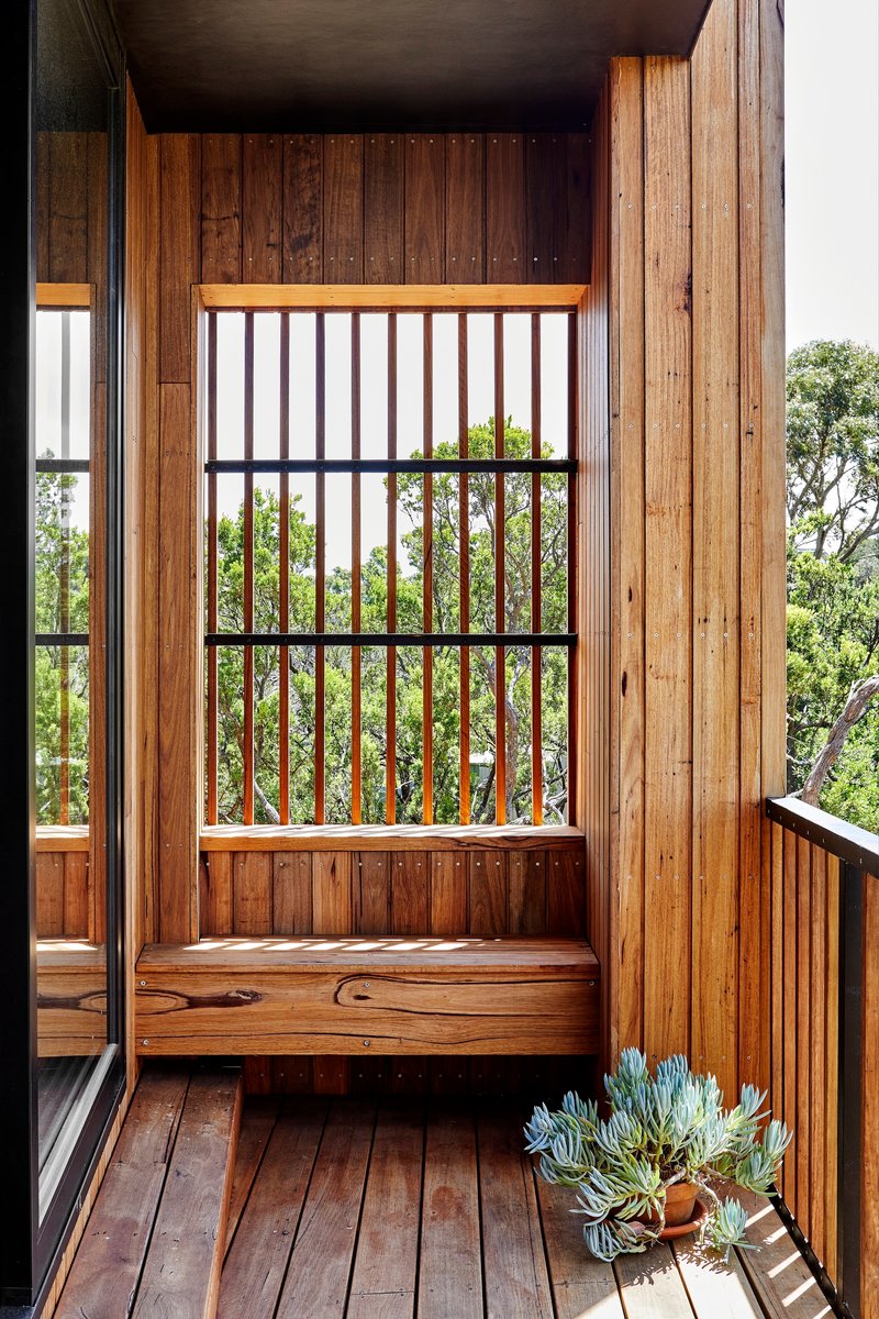 Built-in window seat with vertical timber slat screen framing views of surrounding vegetation