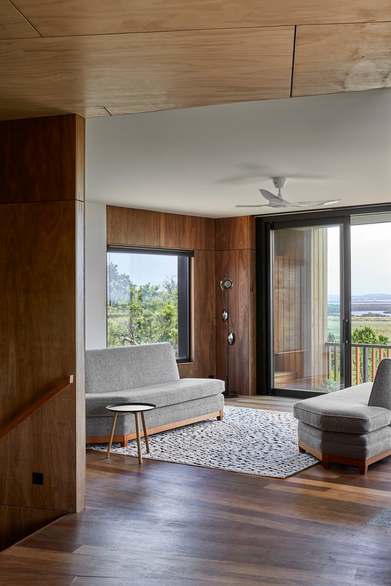 Living room with timber ceiling and floor-to-ceiling glazing framing coastal views