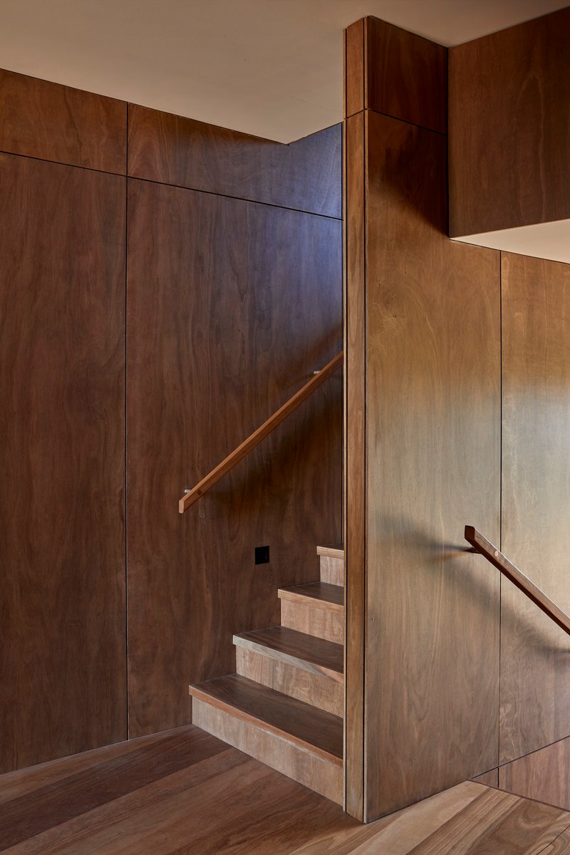 Close view of the staircase corner where dark and light timber panels meet at a vertical edge