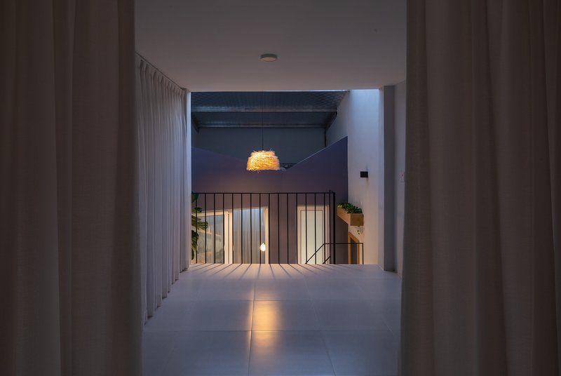 Upper-level corridor at dusk with black steel railing and woven pendant light overhead
