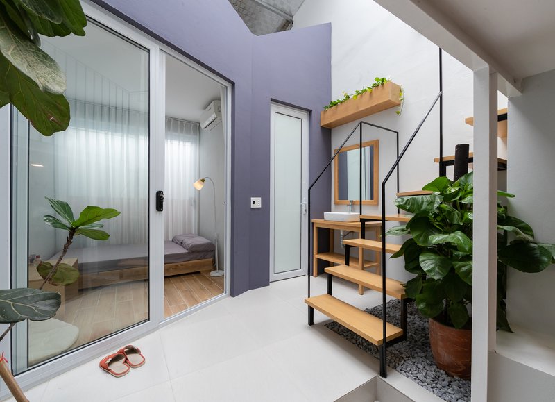 Interior courtyard with timber shelving unit, pebble bed, and potted plants beside glazed bedroom