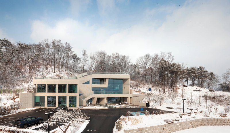 Concrete volumes stepping down a snowy hillside with bare trees in the background