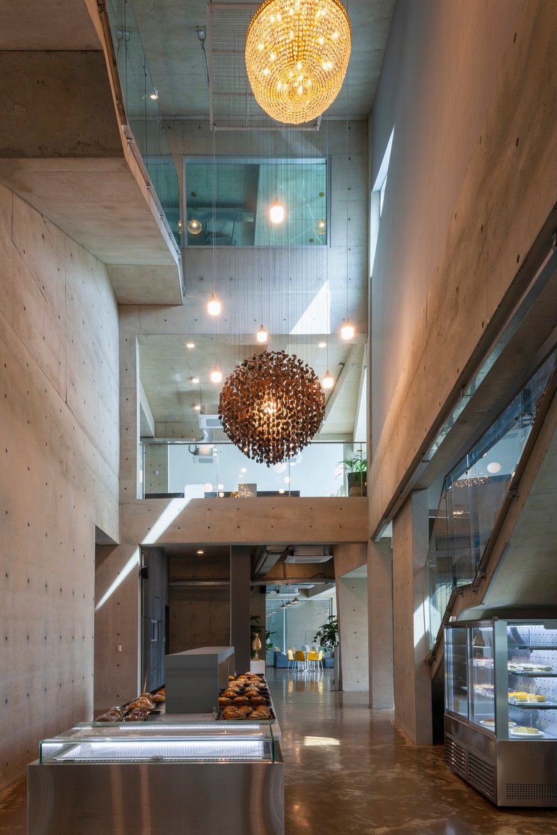 Vertical view through atrium showing stacked concrete floors, glass railings and spherical pendant fixtures
