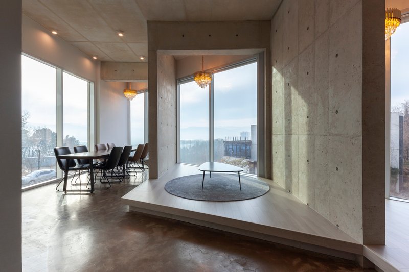 Raised platform seating area with concrete walls and corner windows overlooking winter landscape