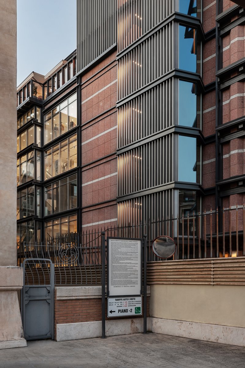 Ground level entrance with horizontal timber slats, metal gate and red brick facade at dusk