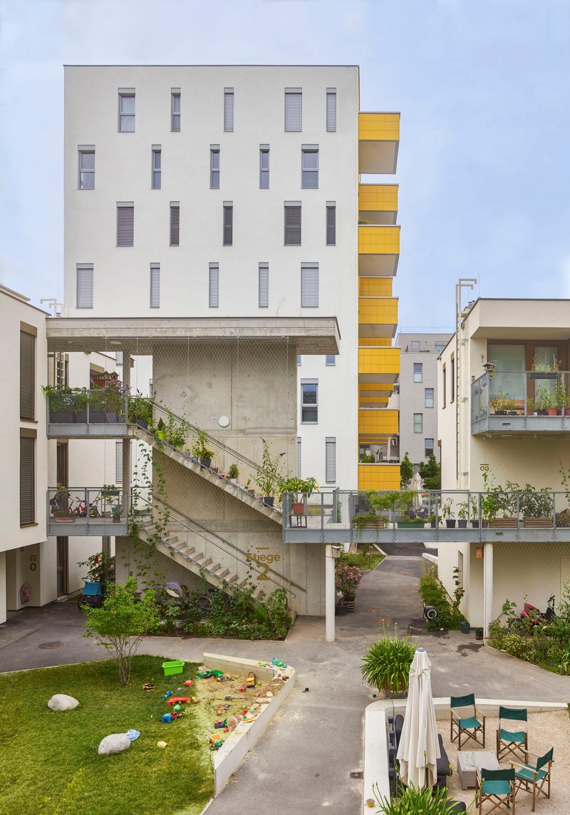 Diagonal concrete staircase connecting courtyard levels with planted balconies and play area below
