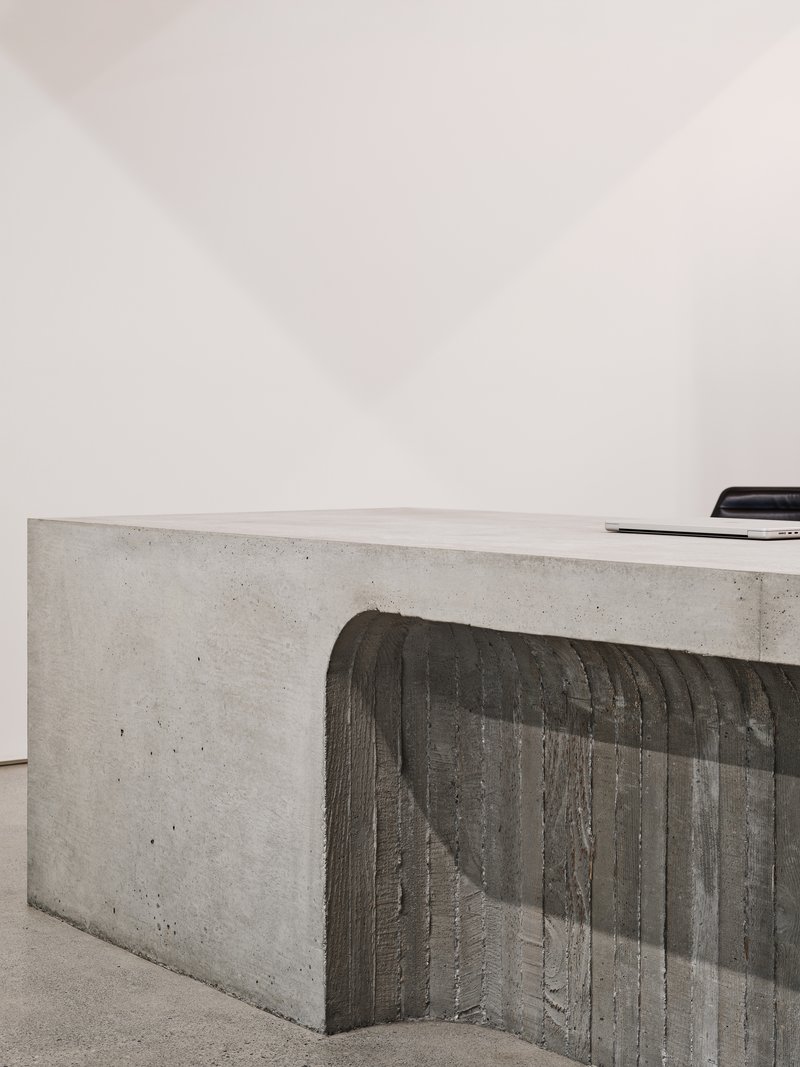 Close-up of board-formed concrete counter with vertical timber texture against a white wall