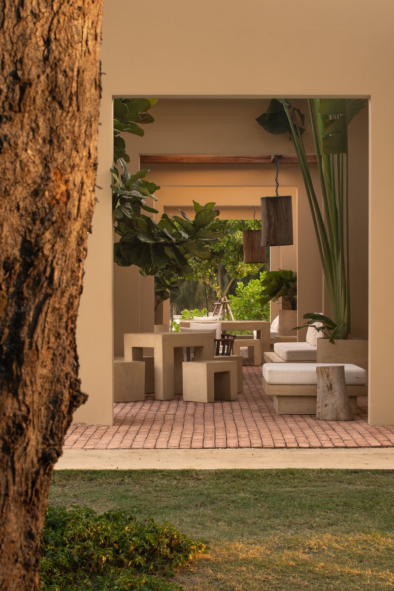 View through the entry opening to a brick-paved terrace with sculptural furniture and potted plants