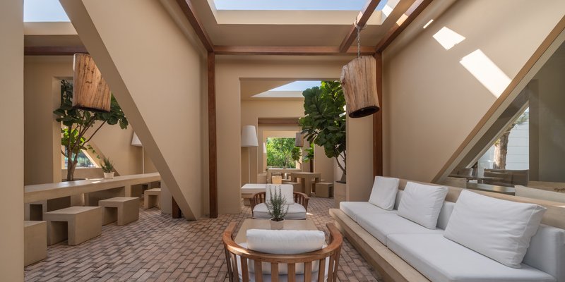 Seating area beneath timber roof beams and rectangular skylights with planters and built-in benches