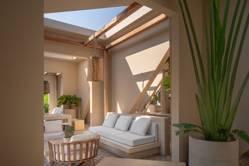 Interior courtyard with timber beam structure, skylights, and geometric shadows on stucco walls