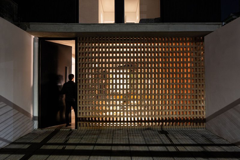 Backlit perforated brick screen with figure in doorway at dusk