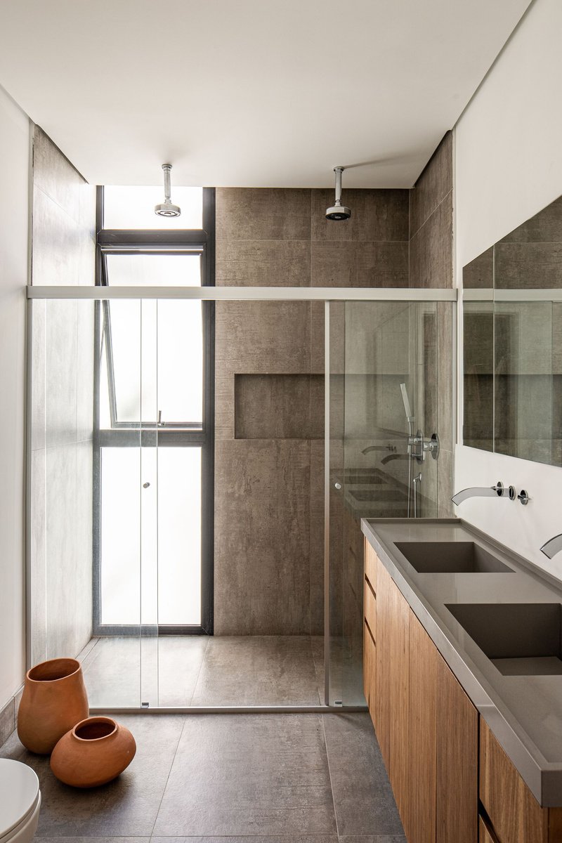Bathroom with glass-enclosed shower and timber vanity beneath a high clerestory window