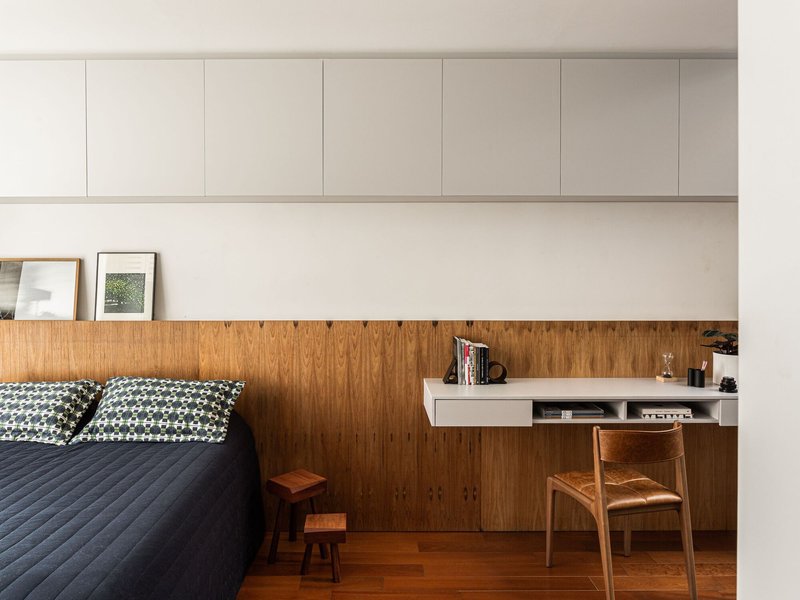 Bedroom wall combining timber wainscoting with integrated desk and upper white storage cabinets