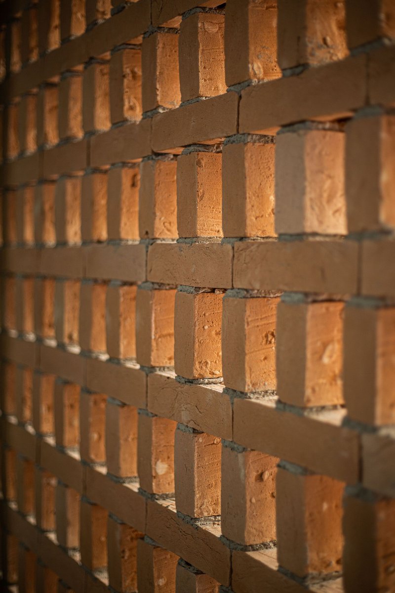 Angled view of stacked brick corners showing mortar joints and textured face in raking sunlight