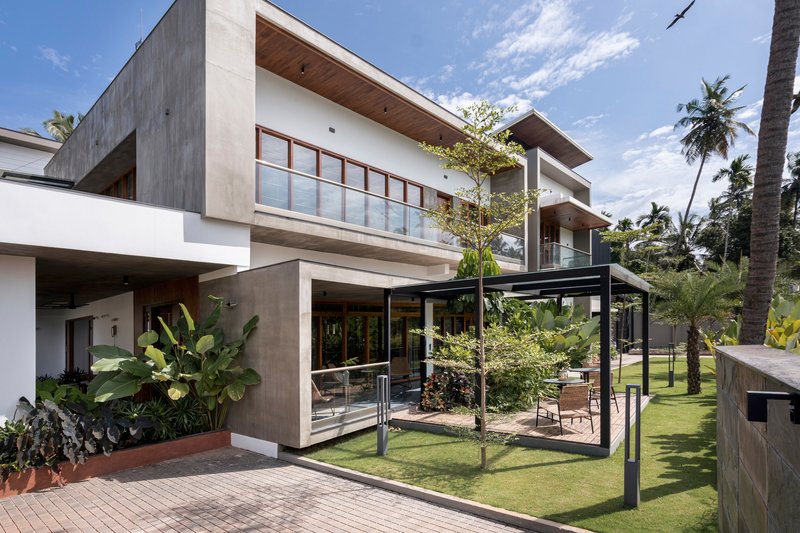 Garden view of the stacked concrete and white volumes with steel-framed pergola surrounded by palm trees