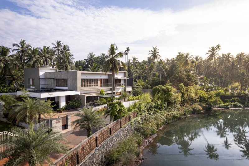 Elevated view of the terraced concrete volumes stepping down to a pond bordered by tropical vegetation