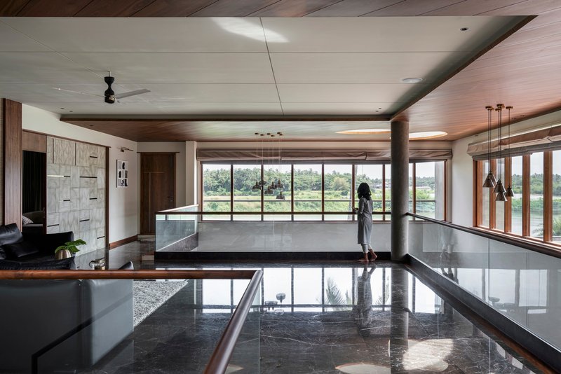 Upper-level interior with polished stone floor, timber ceiling panels, and a person standing at the window