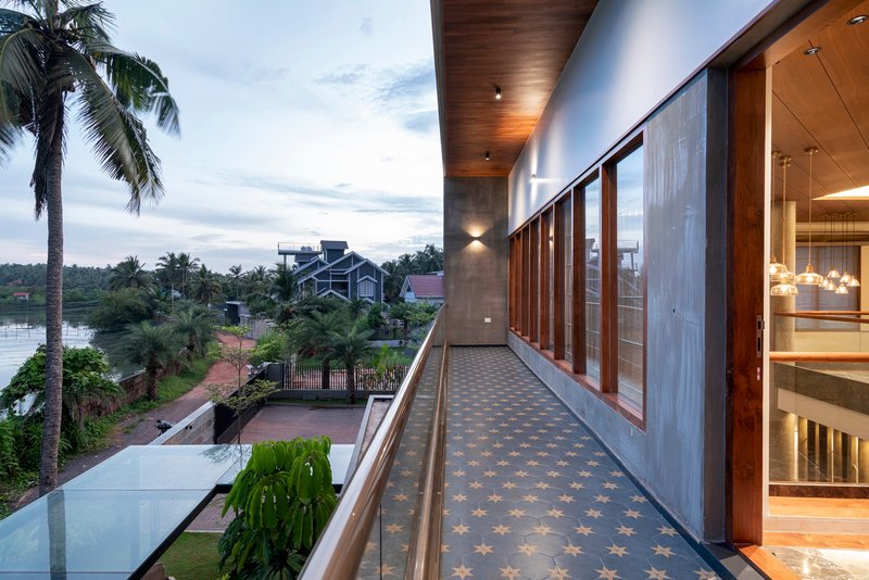 Exterior corridor at dusk with patterned tile floor, timber ceiling soffit, and timber screens beside palm trees
