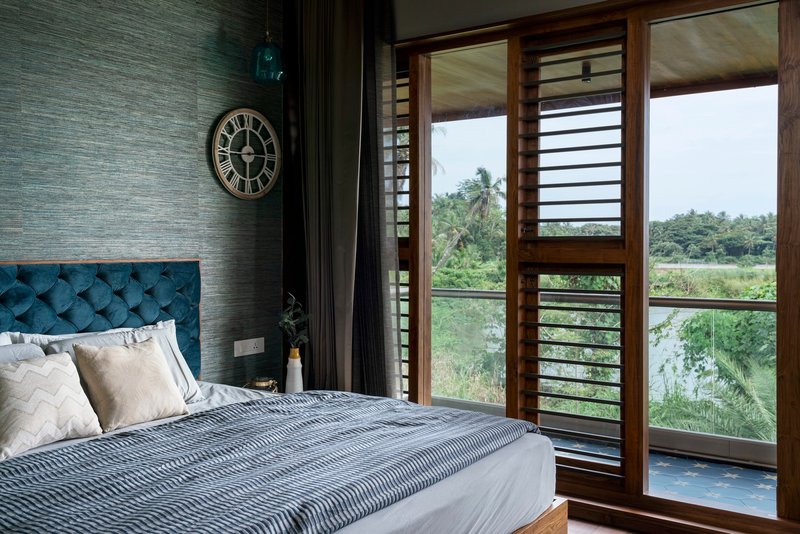 Bedroom with textured grey wall and timber louvered doors opening to a balcony beyond
