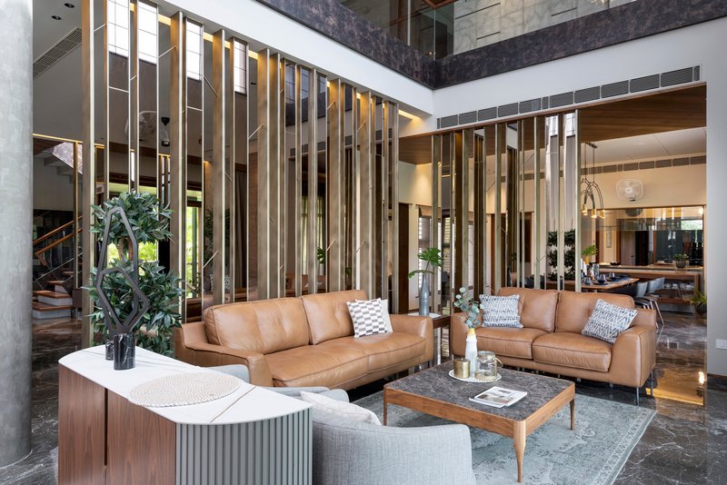Living area with vertical brass and timber screen dividing the double-height interior courtyard