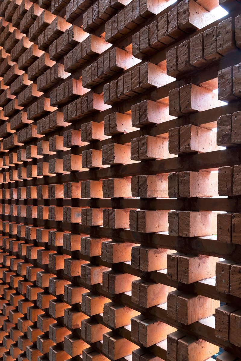 Perforated brick screen wall with staggered bonding pattern creating gaps of light and shadow