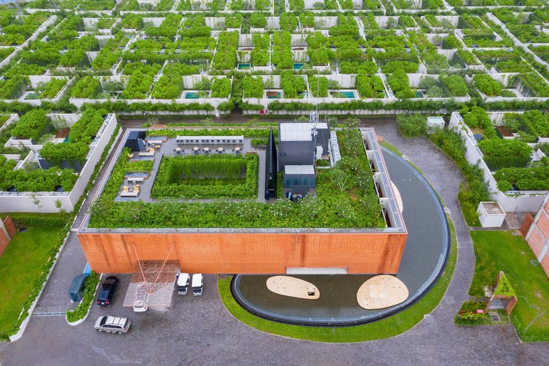 Aerial view of the green-roofed brick building within a grid of planted neighborhood plots