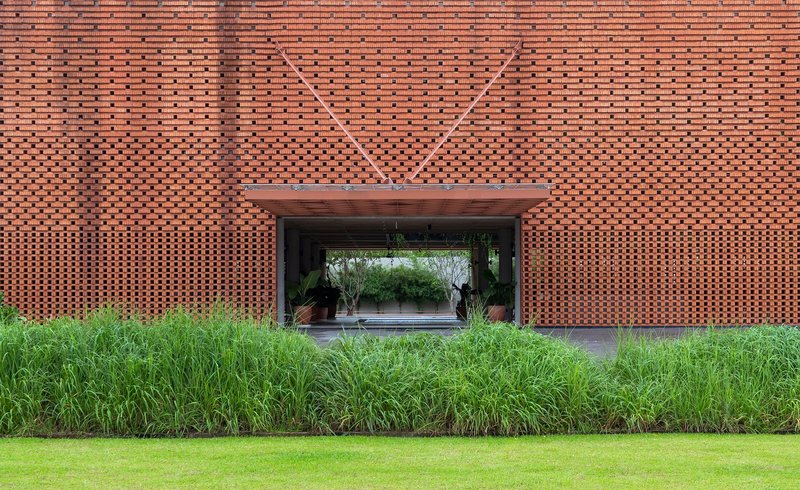 Straight-on view of covered entrance through perforated brick facade with geometric relief pattern