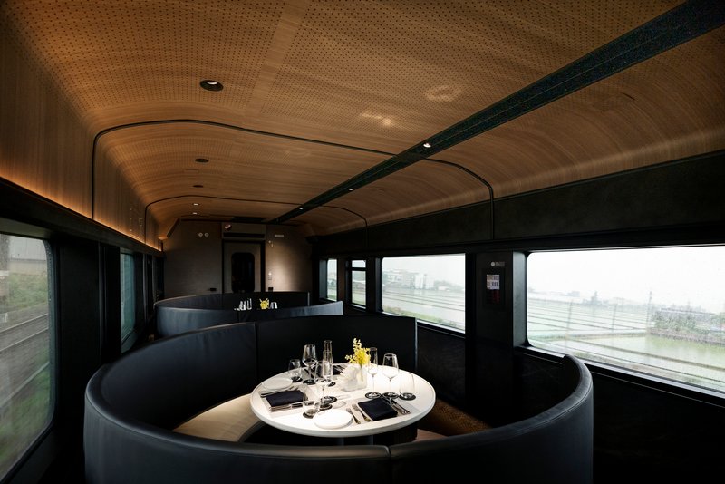 Circular banquette booth with set table and large windows framing an overcast urban landscape outside