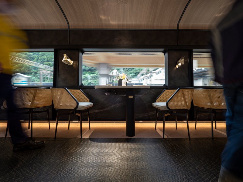 Train carriage dining booth with cane chairs and motion blur of passenger and passing landscape