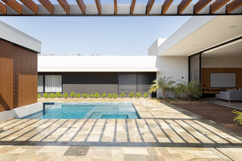 Central courtyard pool framed by white walls and timber pergola beams casting striped shadows