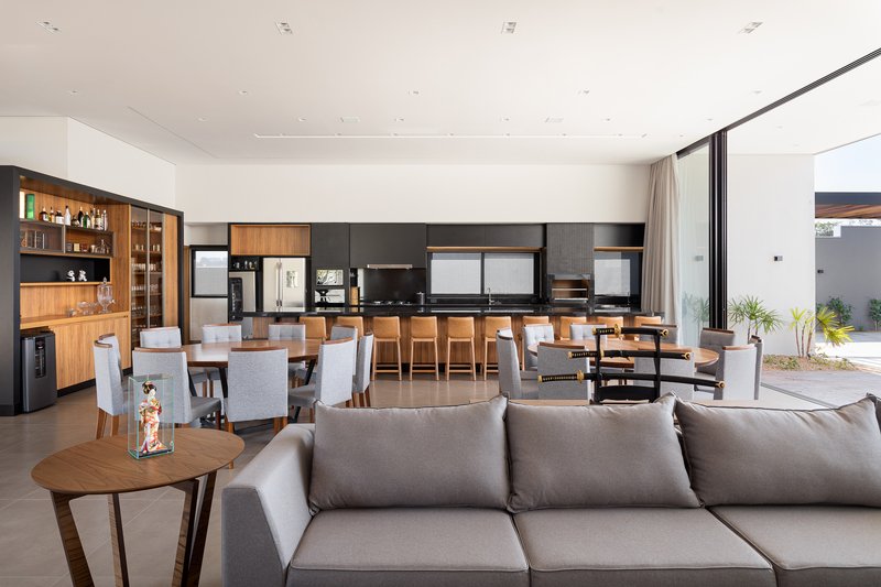Open-plan living and dining area with timber cabinetry, grey upholstered seating, and sliding glass doors opening to a courtyard