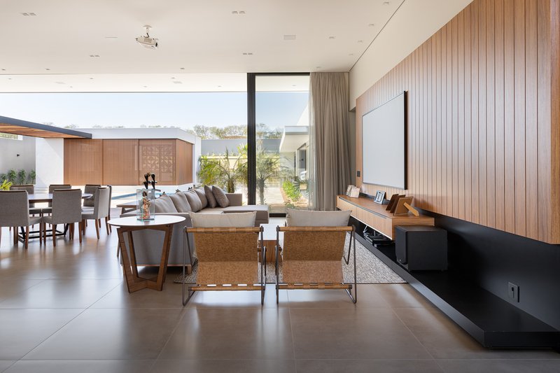 Living room with vertical timber wall paneling, large-format floor tiles, and full-height glazing framing the landscape