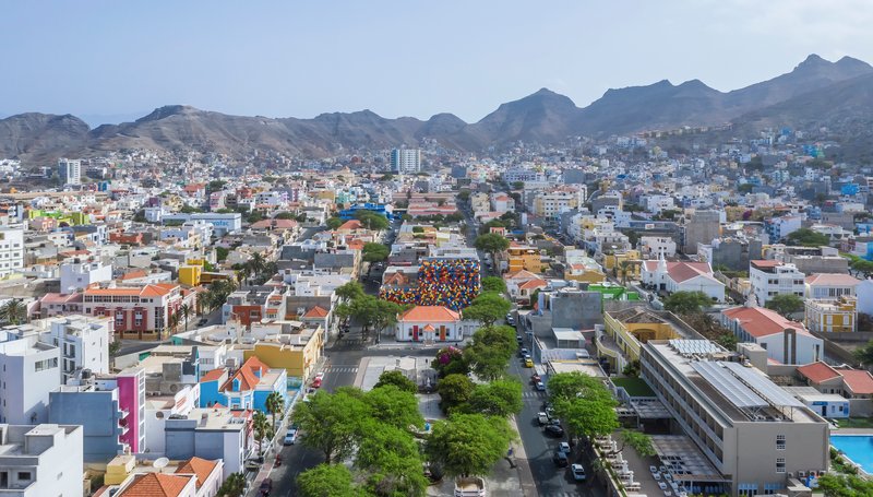 Distant aerial view showing the multicolored volume embedded within the hillside neighborhood fabric