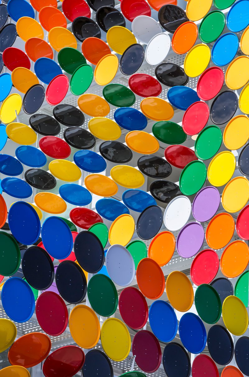 Close-up of multicolored oval glass lenses set in perforated metal screen in bright daylight