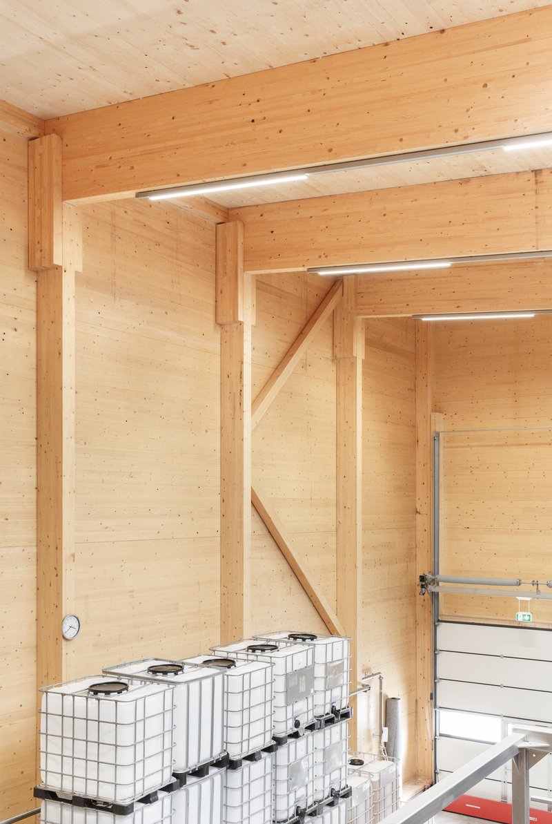 Corner detail of timber post and beam frame with white storage containers at floor level