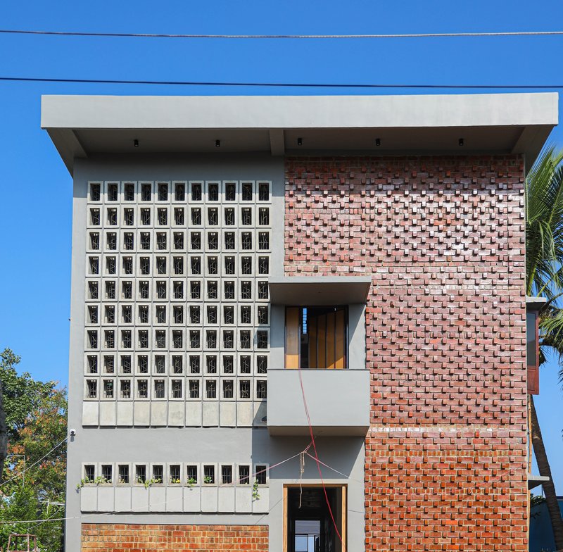 Front elevation showing white concrete block screen and staggered brick facade against bright blue sky
