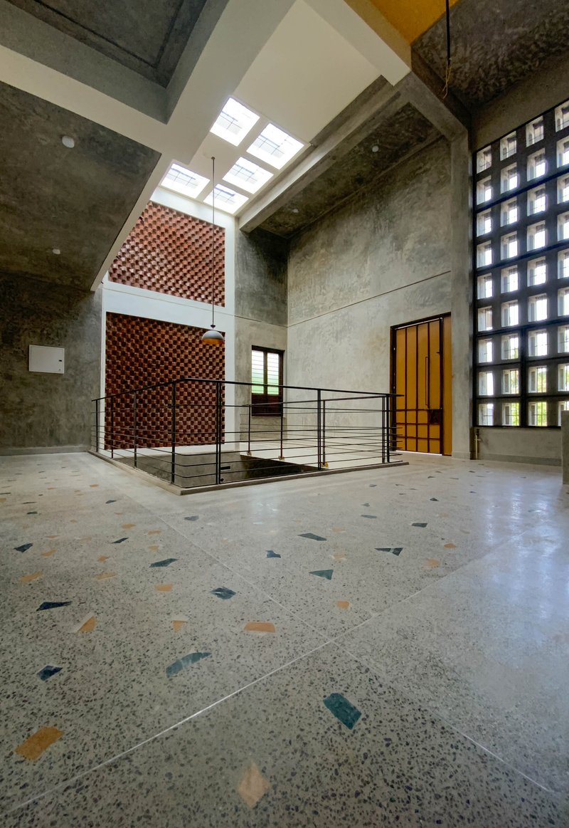 Interior atrium with terrazzo floor, concrete walls, and perforated brick screen in natural daylight