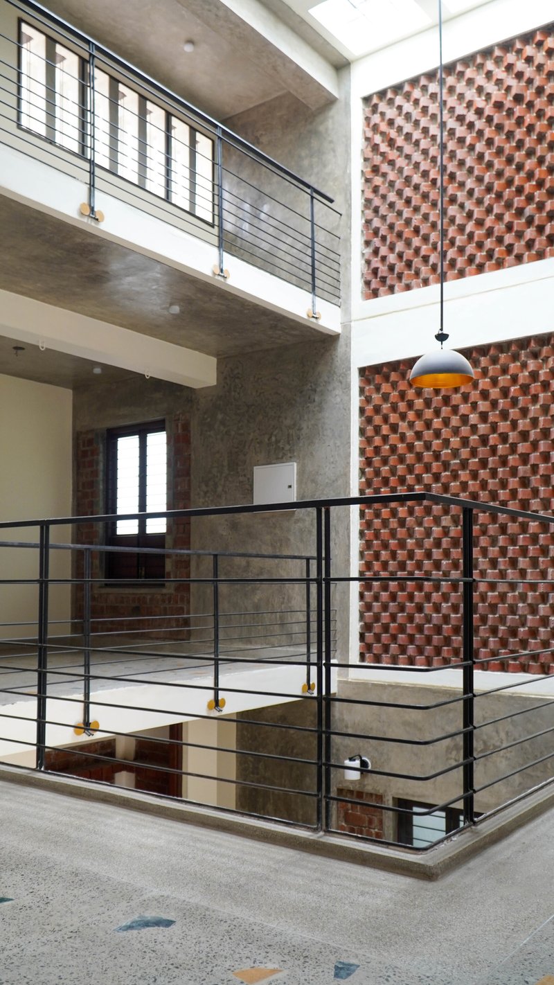 Metal railing around the central stairwell with a pendant light and chequered brick wall behind