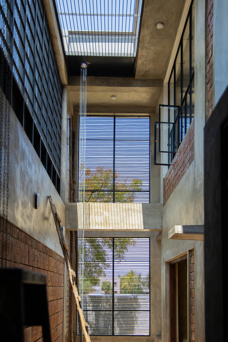 Double-height interior courtyard with horizontal louvered screen framing trees outside