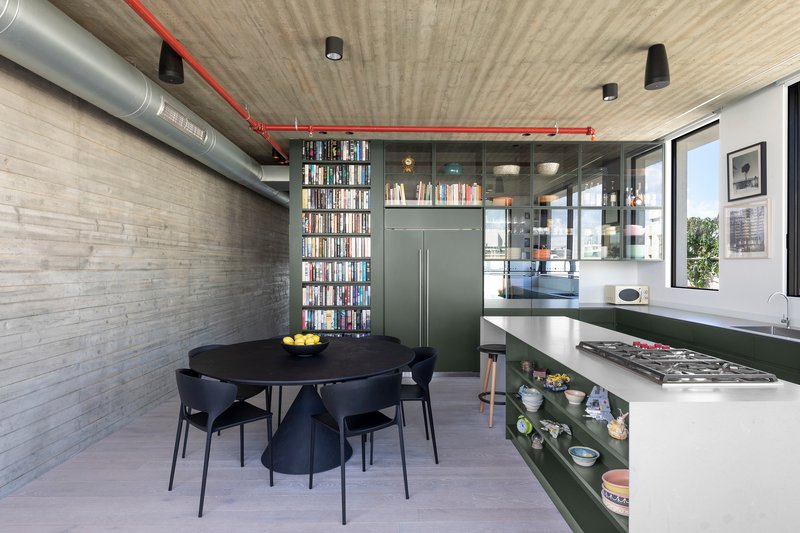 Open kitchen and dining area with exposed red conduit and ductwork beneath a board-formed concrete ceiling